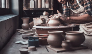 Young man making ceramic pot on the pottery wheel