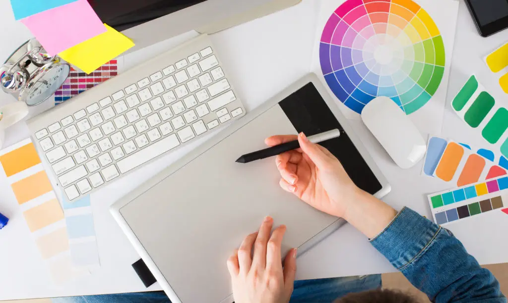 Graphic designer using graphics tablet to do her work at desk