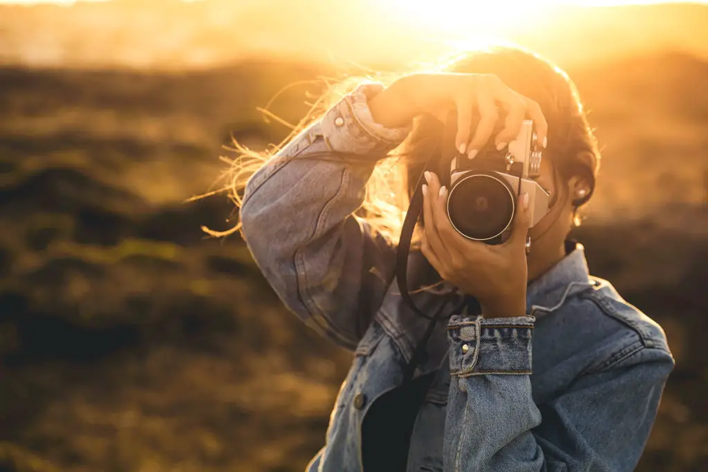 Woman taking pictures outdoors with an analog camera